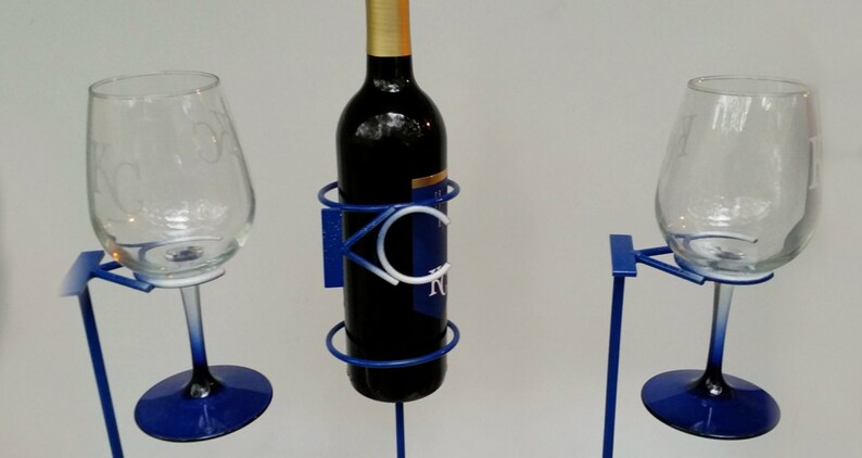 May include: A blue metal wine rack with two wine glasses. The rack has a circular design and the words "KC Royals" are visible on the front.