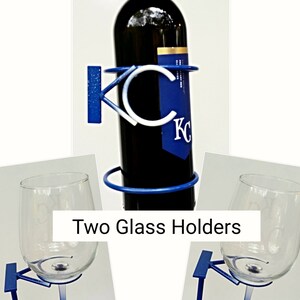 May include: A blue metal wine bottle holder with the letters "KC" in white. Two matching blue metal glass holders are also included.