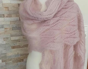Puede incluir: Un chal rosa pálido con un tejido calado. Se muestra sobre un maniquí, resaltando su textura suave y diseño fluido. El color rosa claro crea una estética suave y aireada. Un accesorio femenino y ligero.