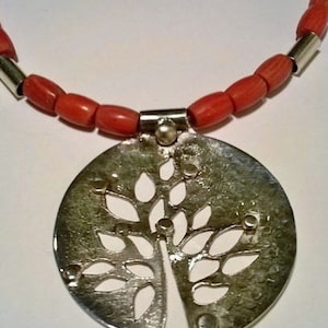 May include: A silver necklace with a tree-shaped pendant and red coral beads.