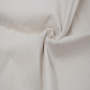 May include: A close-up of a piece of off-white fabric with a slightly textured surface. The fabric is folded and wrinkled, showing its natural drape.