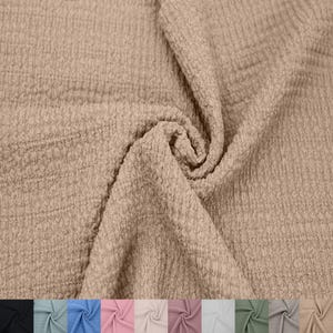 May include: A close-up of a beige textured fabric. The fabric is soft and has a crinkled look. It is perfect for sewing projects, such as clothing, blankets, and home decor.