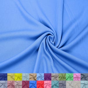 Op de afbeelding: Een close-up van een lichtblauwe stof, die de textuur en de drapeert toont. De stof is verkrijgbaar in verschillende kleuren, waaronder groen, roze, paars en grijs.