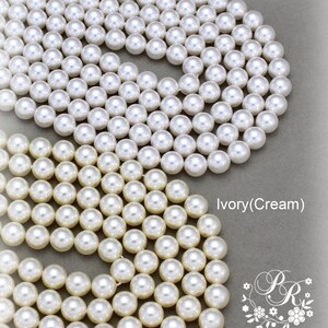 May include: Two strands of pearl beads, one white and one ivory (cream). The beads are arranged in a circular pattern.