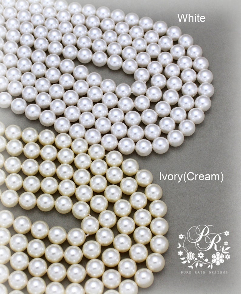 May include: Two strands of pearl beads, one white and one ivory (cream). The beads are arranged in a circular pattern.