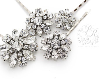 May include: Three silver-toned hair pins featuring floral-shaped clusters of clear, faceted crystals in round and marquise cuts. The metal pins are thin and wavy. A logo with the text PR PURE RAIN DESIGNS is visible in the lower right corner.