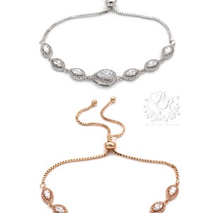 May include: Two adjustable bracelets. The top bracelet is silver-toned, and the bottom bracelet is rose gold-toned. Both bracelets feature a series of clear, sparkling stones in a marquise and pear shape. The bracelets are on a white background.