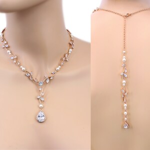 May include: A rose gold bridal necklace with a pear-shaped crystal pendant and delicate leaf accents. The necklace is also available as a back-drop necklace with a long chain.