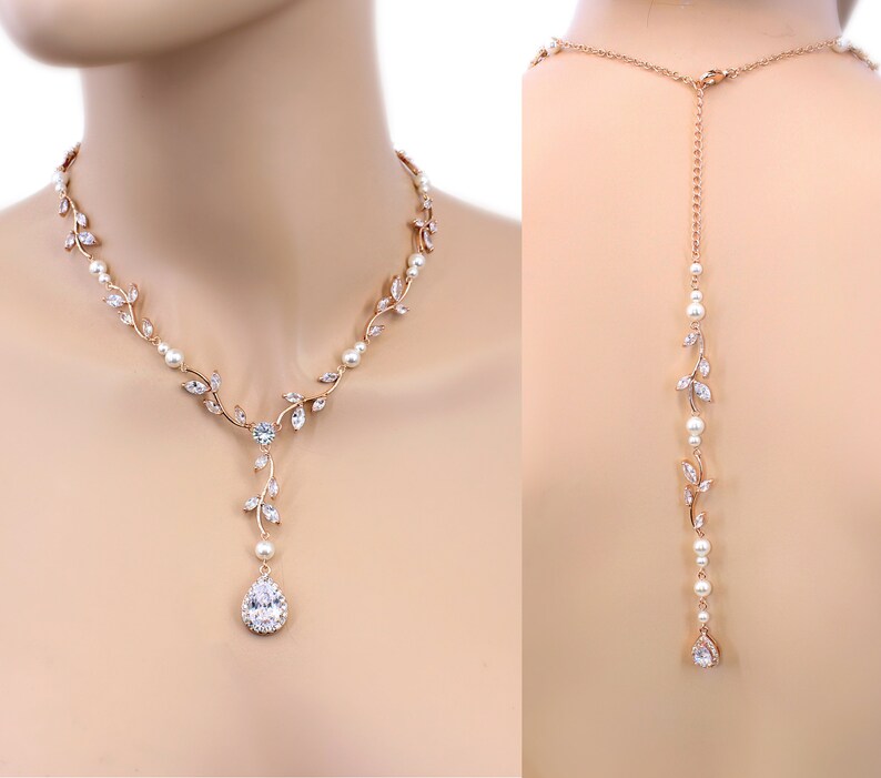 May include: A rose gold bridal necklace with a pear-shaped crystal pendant and delicate leaf accents. The necklace is also available as a back-drop necklace with a long chain.