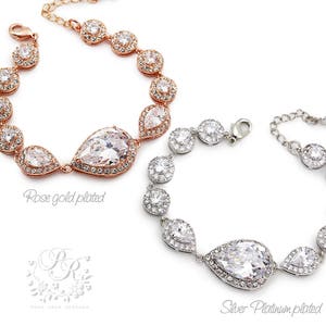 K&ouml;nnte beinhalten: Zwei Kristall-Brautarmreifen mit tropfenf&ouml;rmigen Mittelsteinen. Ein Armband ist ros&eacute;vergoldet und das andere ist silberplatiniert.