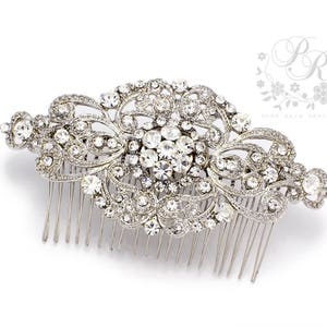 May include: Silver hair comb with a large, ornate design featuring a cluster of clear rhinestones. The comb has a delicate, floral pattern and is perfect for adding a touch of sparkle to any hairstyle.