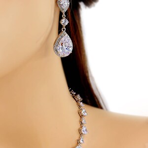 May include: A silver necklace and earrings set with teardrop-shaped cubic zirconia stones. The necklace has a long, delicate chain with a single teardrop stone at the bottom.