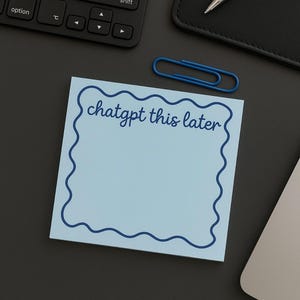 May include: A light blue sticky note with a wavy dark blue border and the text "chatgpt this later" in cursive. A blue paper clip, a keyboard, a pen, and a black notebook are also visible.