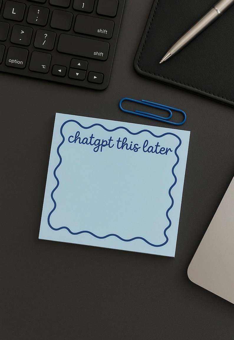 May include: A light blue sticky note with a wavy dark blue border and the text "chatgpt this later" in cursive. A blue paper clip, a keyboard, a pen, and a black notebook are also visible.