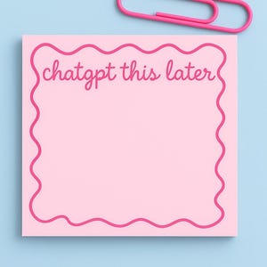 May include: A pink sticky note with a wavy pink border and the text "chatgpt this later" in a handwritten style. A pink paper clip rests above the note on a light blue background. Stationery.