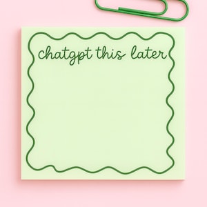 以下が含まれることがあります： 「chatgpt this later」の文字が入った、波型の緑色の縁取りがある薄緑色の付箋。 ピンク色の背景に緑色のクリップが置かれています。