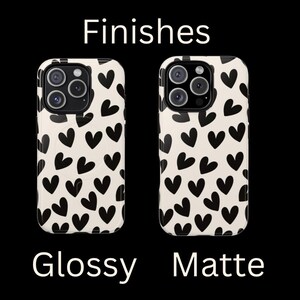 May include: Two iPhone cases with a black and white heart pattern. The case on the left is glossy and the case on the right is matte. Finishes: Glossy, Matte.