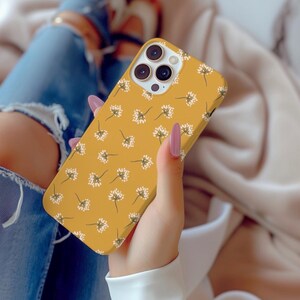 May include: A yellow phone case with a white floral pattern. The case has a camera lens cutout and a raised lip around the edges.