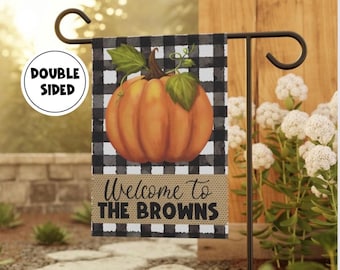 Może przedstawiać: Dwustronna flaga ogrodowa z ilustracją dyni na czarno-białym tle w kratę. Flaga głosi "Welcome to THE BROWNS" na banerze w stylu jutowym. Flaga jest wyświetlana na czarnym metalowym stojaku.