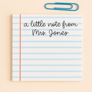 Puede incluir: Un bloc de notas con líneas horizontales azules y el texto "a little note from Mrs. Jones" en escritura negra. Un clip azul está encima del bloc de notas. El bloc de notas tiene una línea vertical roja en el lado izquierdo.