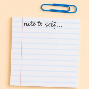 May include: A square white sticky note with horizontal light blue lines and a vertical pink margin line. The text "note to self..." is printed in black cursive script at the top. A single blue metal paperclip rests above the sticky note.