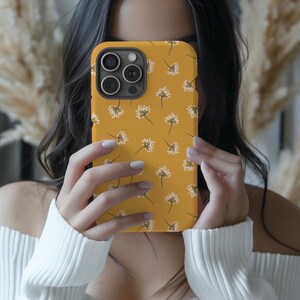 May include: A yellow phone case with a white floral pattern. The case has a camera cutout and is designed for a smartphone.