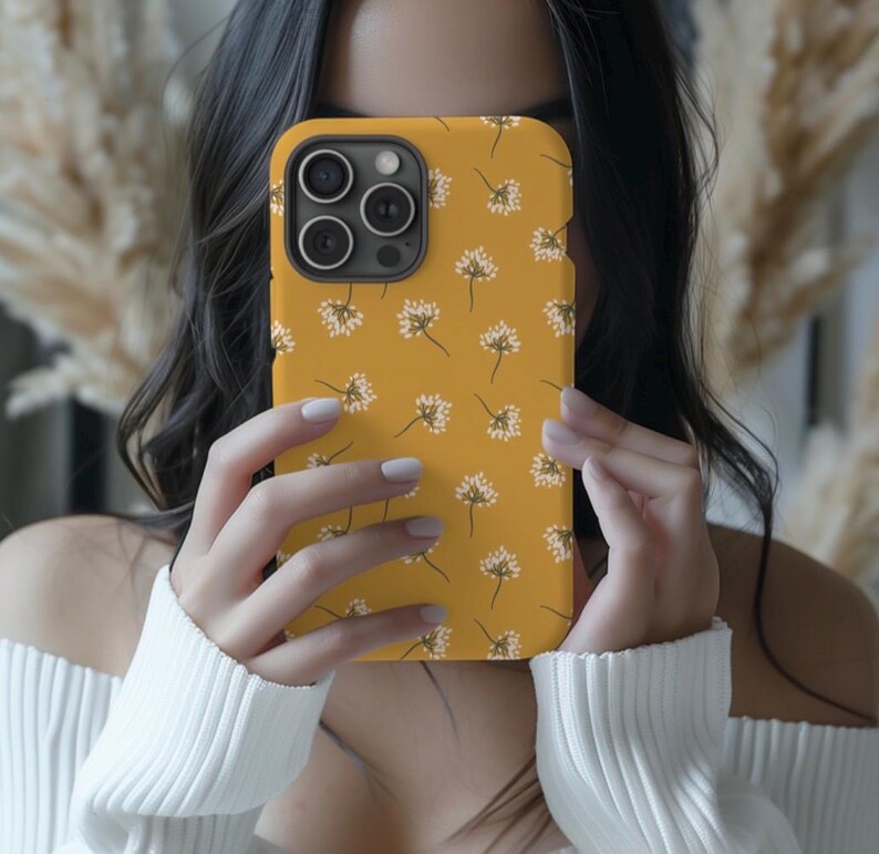 May include: A yellow phone case with a white floral pattern. The case has a camera cutout and is designed for a smartphone.