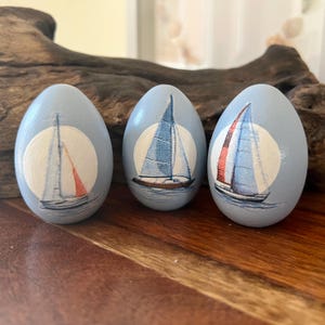 Ovo de Páscoa de madeira personalizado em formato de veleiro azul, decoração de primavera para praia e litoral.