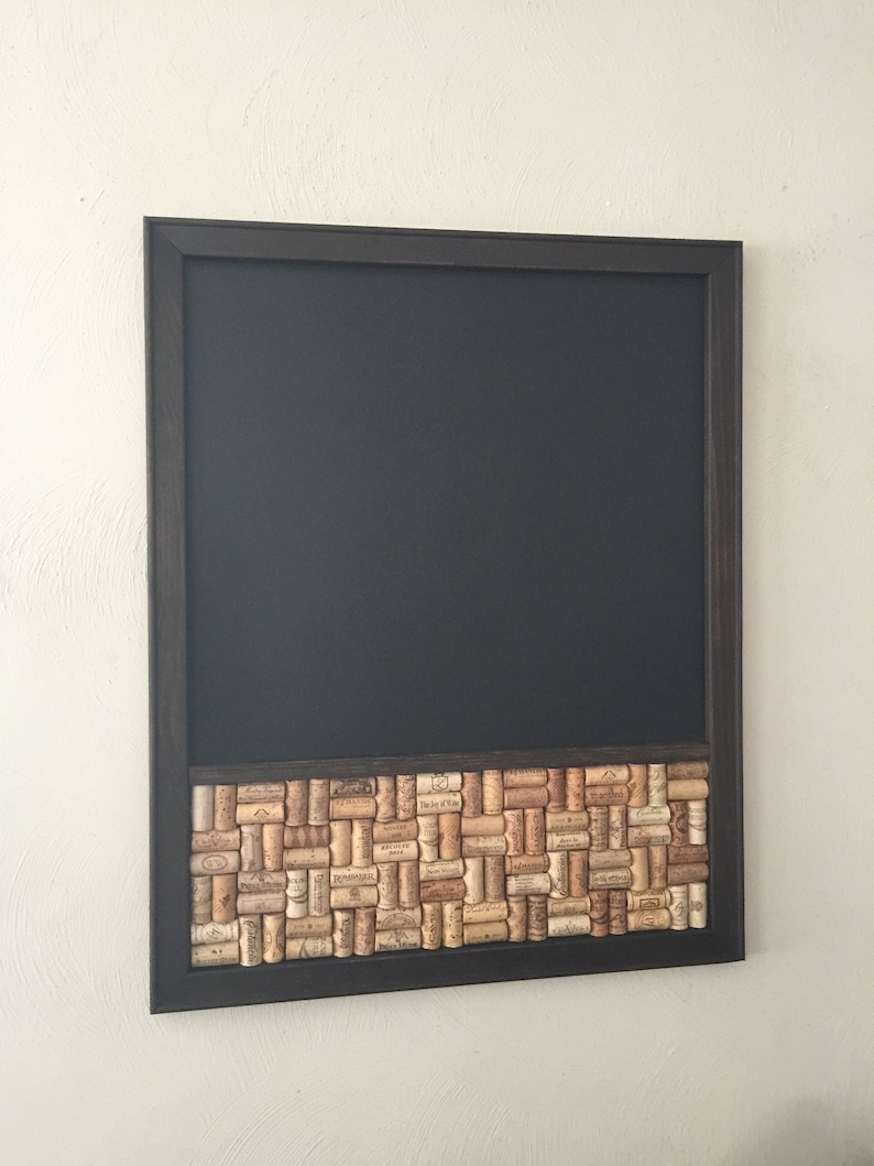 May include: A black framed chalkboard with a cork border. The cork border is made up of wine corks with labels.