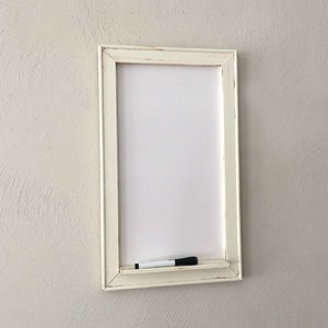 Może przedstawiać: Biała tablica suchościeralna w białej ramie z białym markerem na p&oacute;łce pod tablicą.