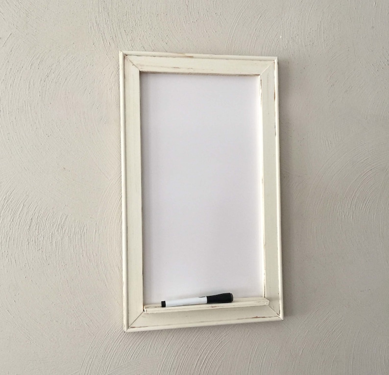 Może przedstawiać: Biała tablica suchościeralna w białej ramie z białym markerem na p&oacute;łce pod tablicą.