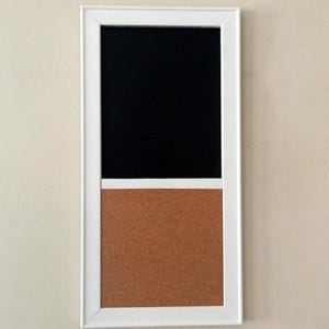 Könnte beinhalten: Ein rechteckiges Whiteboard mit weißem Rahmen, das eine schwarze Tafel und eine braune Pinnwand kombiniert. Der obere Teil ist eine schwarze Tafel, der untere Teil ist eine braune Pinnwand. Das Board hängt an einer beigen Wand.