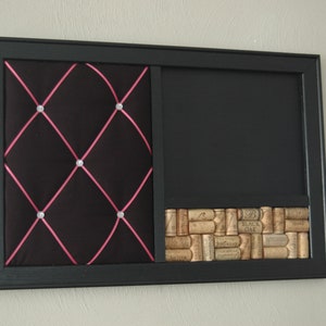 Puede incluir: Un tablero de corcho negro enmarcado con una secci&oacute;n de tela capiton&eacute;, una secci&oacute;n de pizarra y una secci&oacute;n inferior cubierta de corchos de vino. La secci&oacute;n de tela tiene una cinta rosa y diamantes de imitaci&oacute;n.