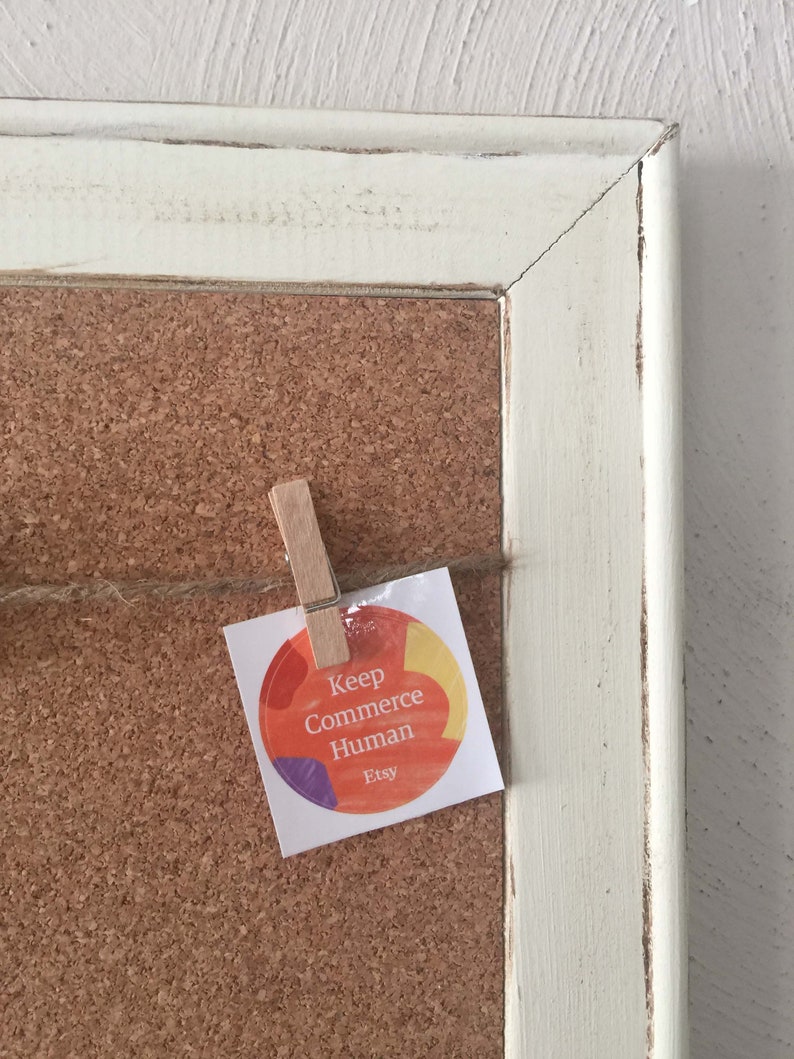 Puede incluir: Un tablero de corcho con un marco blanco y una pegatina que dice "Keep Commerce Human Etsy" con un dise&ntilde;o abstracto colorido.