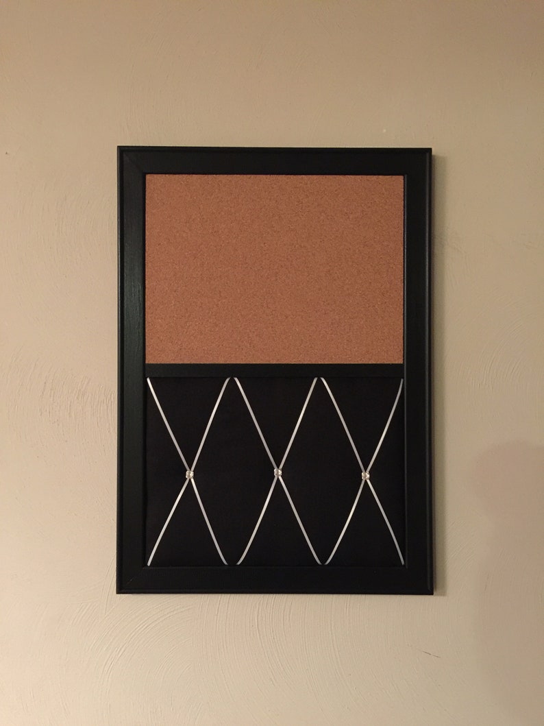 Puede incluir: Un tablero de corcho con marco negro y una secci&oacute;n inferior de tela negra con un patr&oacute;n de diamante y acentos plateados.