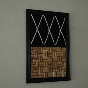 Puede incluir: Un tablero de corcho enmarcado en negro con una cinta blanca cruzando la secci&oacute;n superior y un patr&oacute;n de baldosas de corcho en la secci&oacute;n inferior.