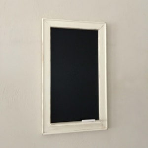 Może przedstawiać: Czarna tablica z białą ramą, z czarną powierzchnią i kawałkiem białej kredy na dolnej krawędzi.