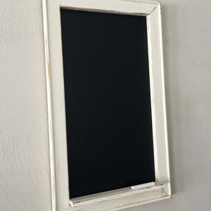 Może przedstawiać: Czarna tablica z białą ramą, z białą p&oacute;łką na kredę i kawałkiem białej kredy na p&oacute;łce.