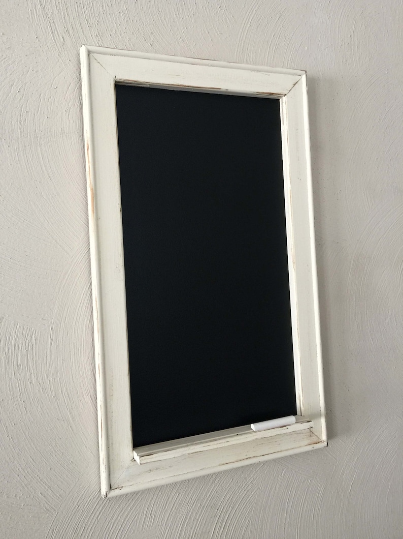 Może przedstawiać: Czarna tablica z białą ramą, z białą p&oacute;łką na kredę i kawałkiem białej kredy na p&oacute;łce.