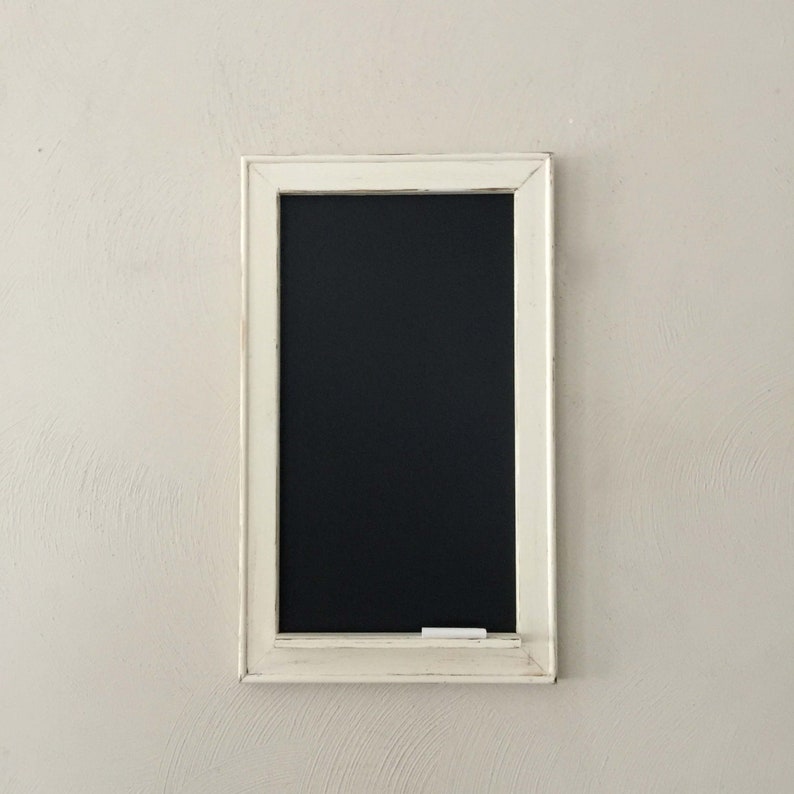 Może przedstawiać: Czarna tablica z białą ramą, z czarną powierzchnią i kawałkiem białej kredy na dolnej krawędzi.