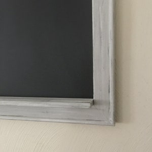 Może przedstawiać: Szara ramka tablicy z ramką z białego malowanego drewna. Rama ma postarzony wygląd z widocznymi pociągnięciami pędzla.