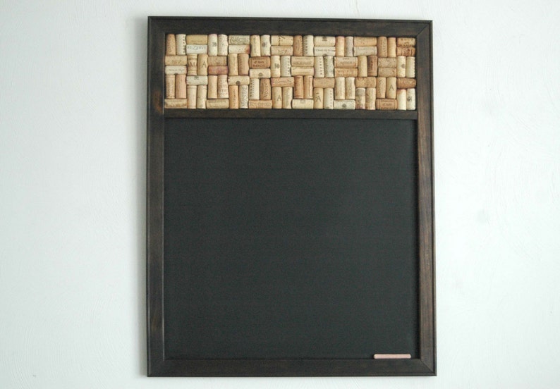 May include: A black chalkboard with a wooden frame and a cork border. The cork border is made of wine corks arranged in a mosaic pattern.