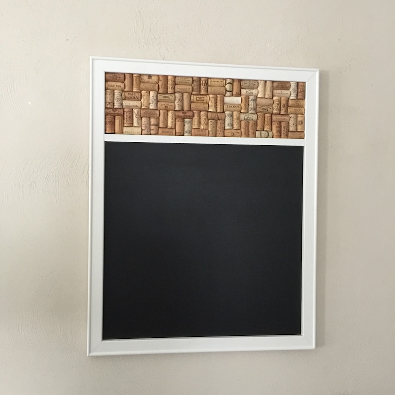 May include: A white framed chalkboard with a cork border made of wine corks. The chalkboard is blank.