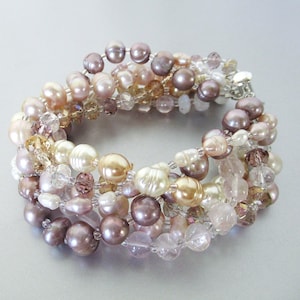 May include: A multi-strand bracelet featuring a mix of pearls in shades of pink, cream, and white, along with clear and rose quartz crystals.