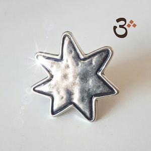 May include: A silver-toned, seven-pointed star charm with a textured surface. The star is slightly raised from the background.