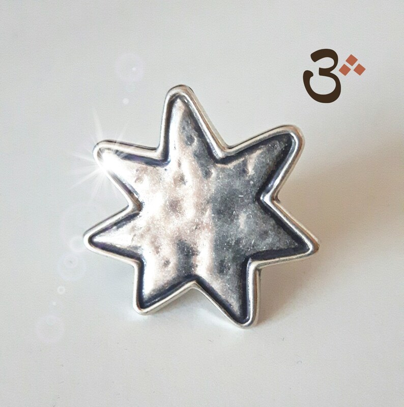 May include: A silver-toned, seven-pointed star charm with a textured surface. The star is slightly raised from the background.