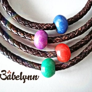 May include: Four leather bracelets with colorful beads. The beads are blue, purple, red, and green.