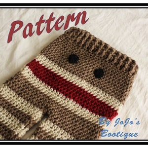 Puede incluir: Patrón de ganchillo para un diseño de calcetín de bebé. El calcetín presenta un patrón de rayas marrones y crema con una raya roja y dos ojos de botón negros. La palabra "Pattern" está escrita en rojo en la parte superior y "By Jojo's Bootique" en la parte inferior.