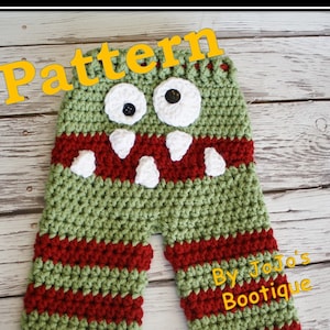 May include: Green and red striped crochet baby pants with a monster face. The monster has white eyes with black pupils and a white mouth with white teeth. The pants are labeled "By JoJo's Boutique".