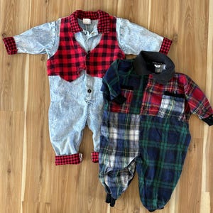 May include: Two vintage baby rompers. One is denim with a red and black plaid vest and trim. The other is a patchwork of red, green, and blue plaid patterns. Both have long sleeves and button closures.